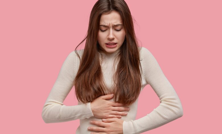 Femme qui se tient le ventre à cause de la douleur